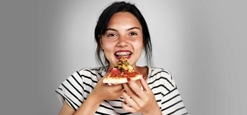 young girl eating pizza with braces